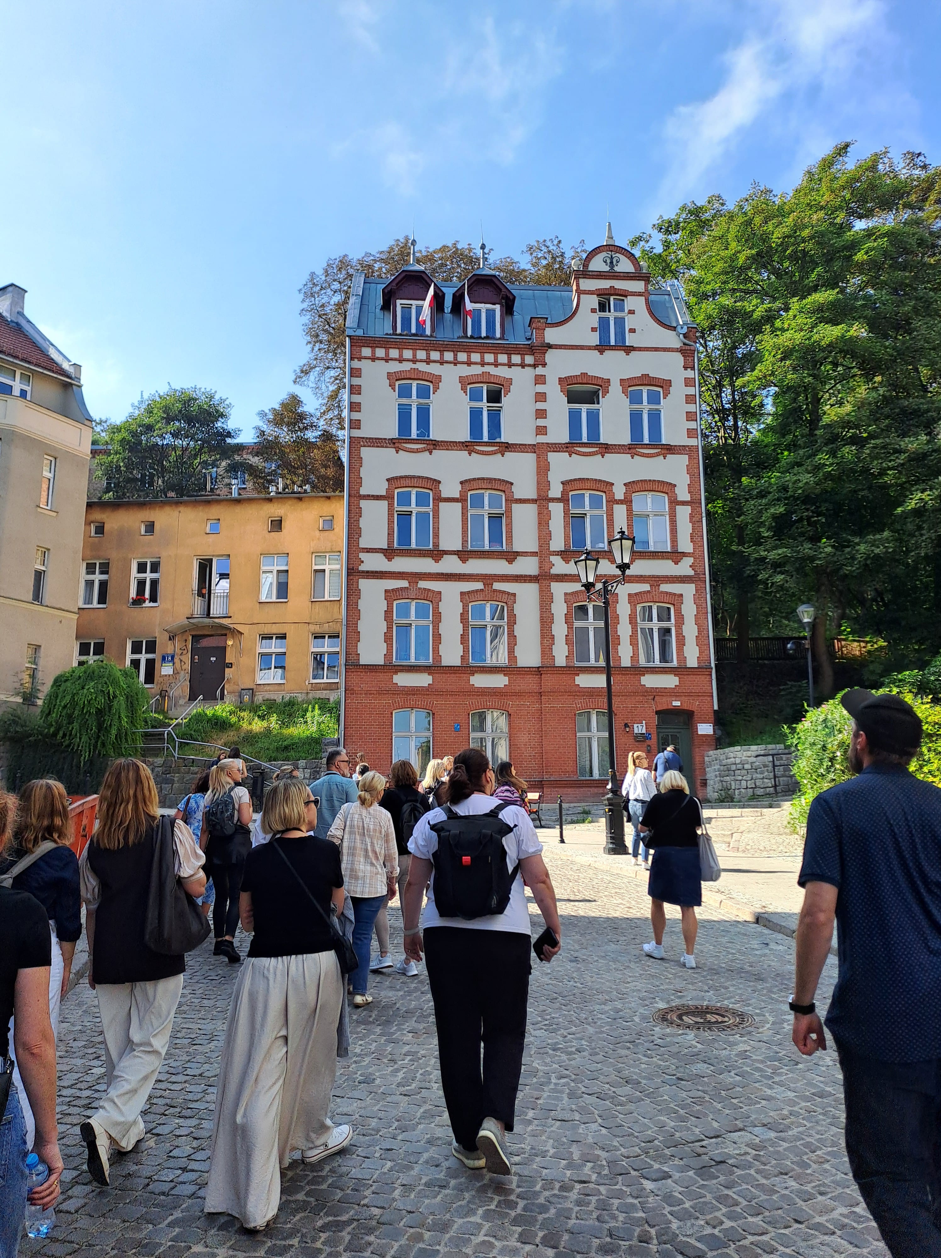 Grupa ludzi na tle zabytkowej kamienicy