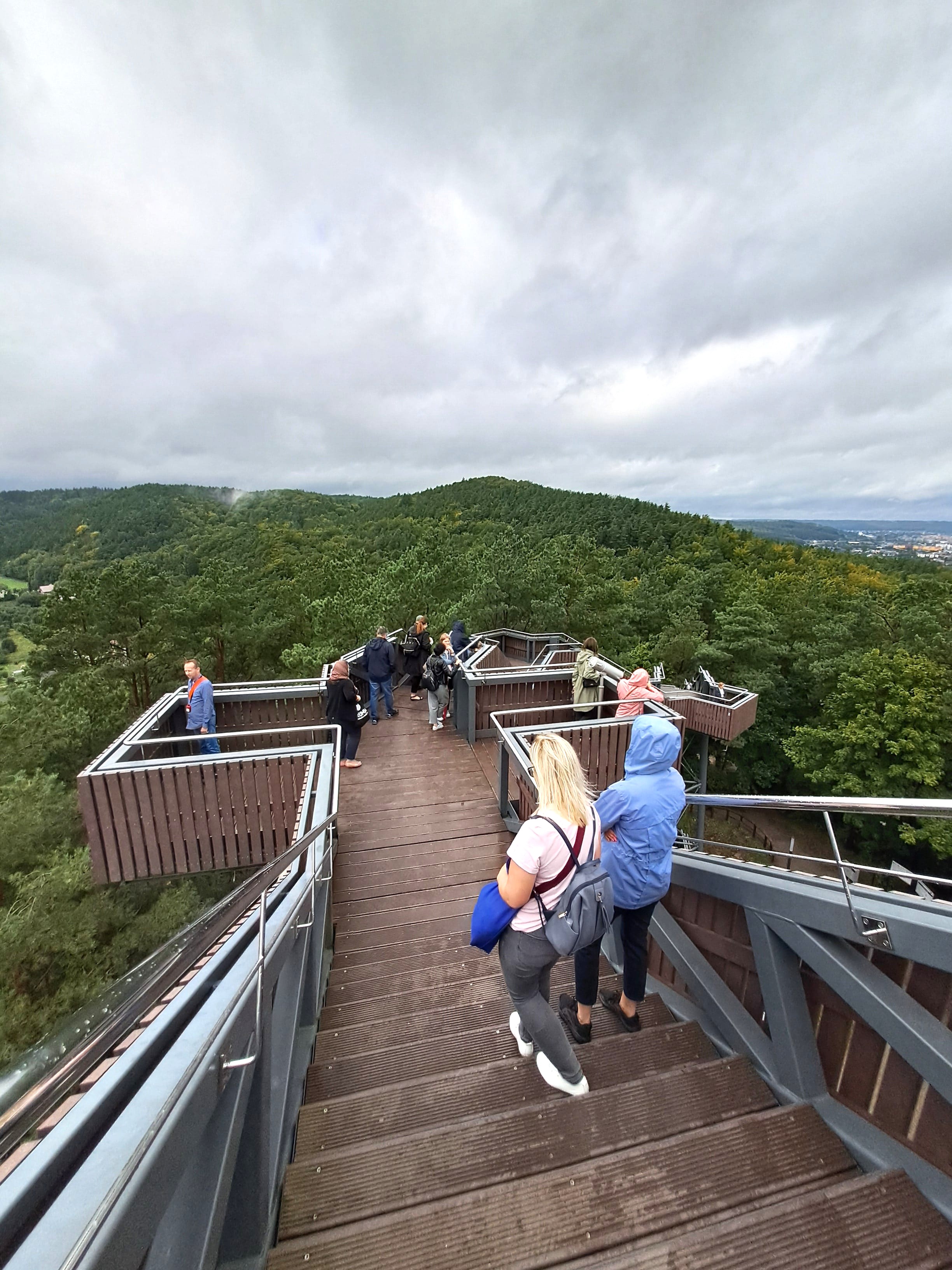 Ludzie na drewnianej kładce na tle niskich gór
