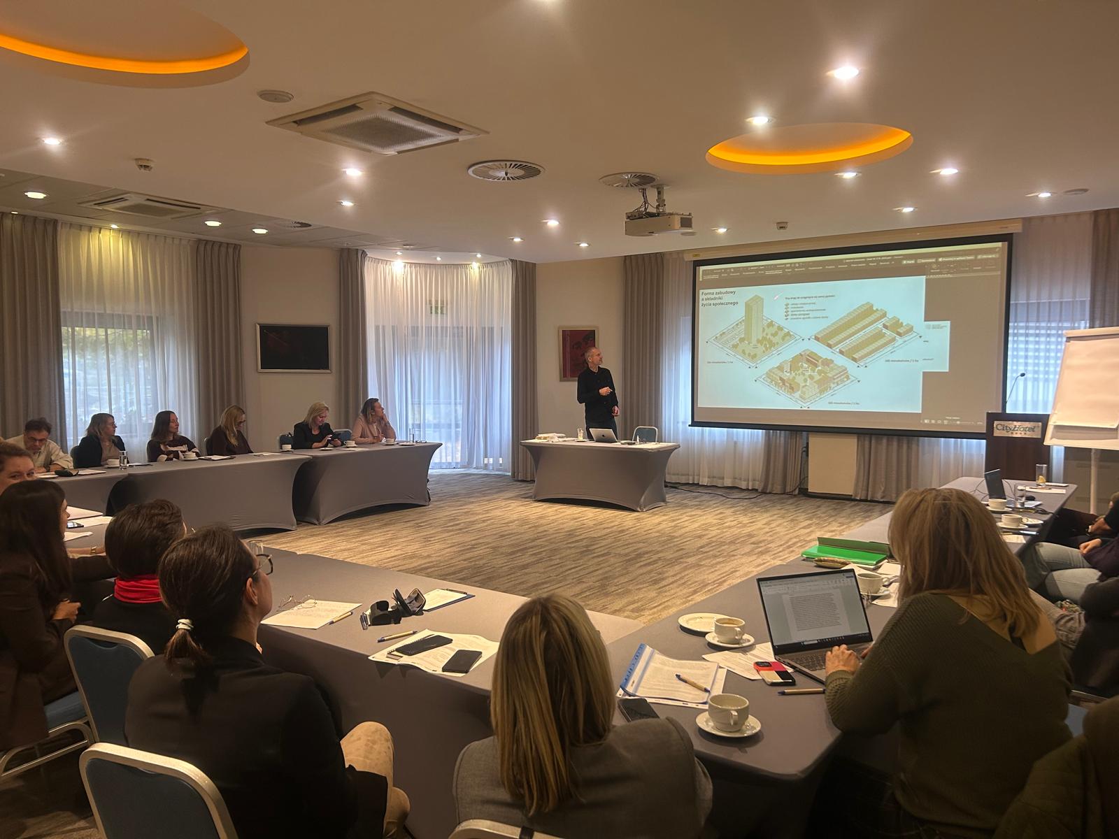 Grupa ludzi słuchająca prezentacji w sali konferencyjnej