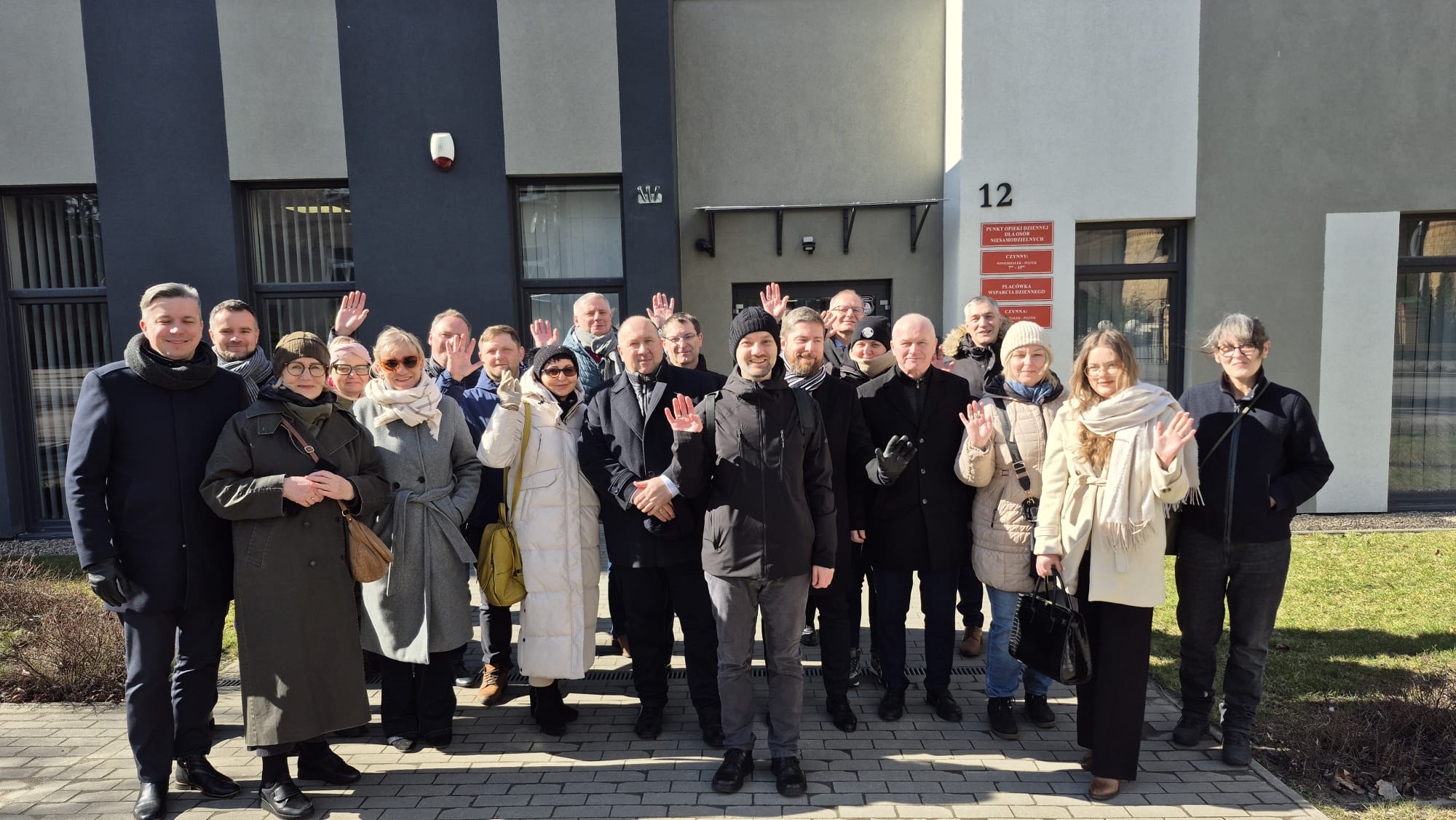 Grupa ludzi stojąca przed budynkiem