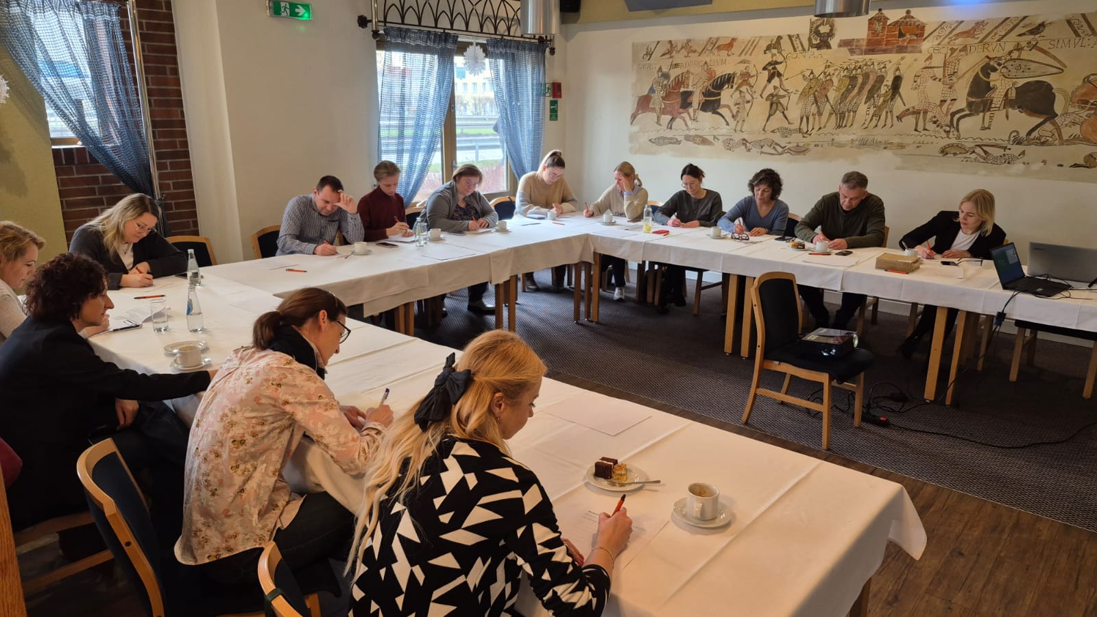 Grupa ludzi siedząca przy stole w kształcie podkowy