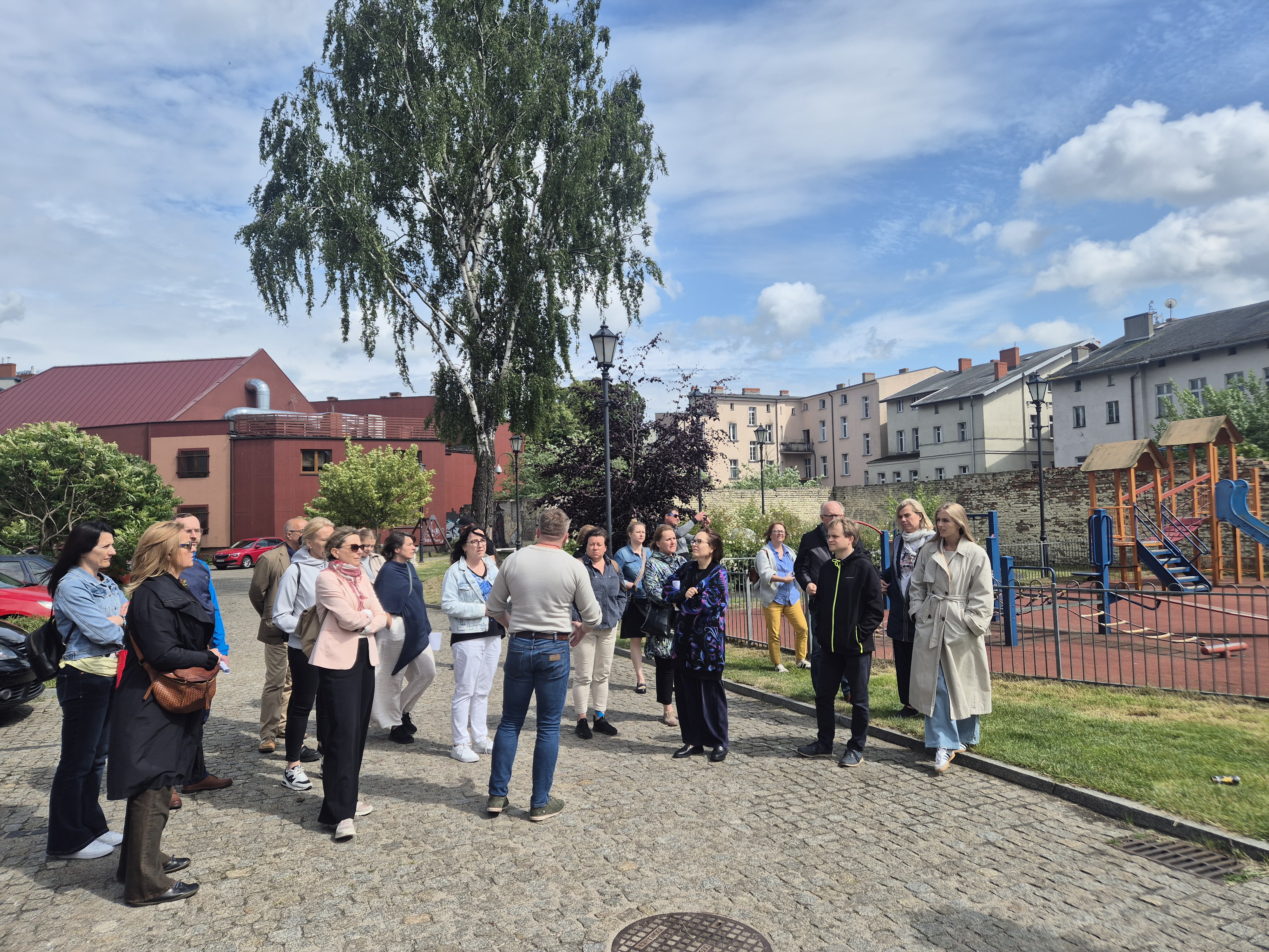 Grupa ludzi stojąca przy placu zabaw