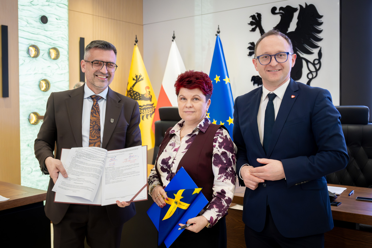 Trzy osoby prezentują podpisaną umowę