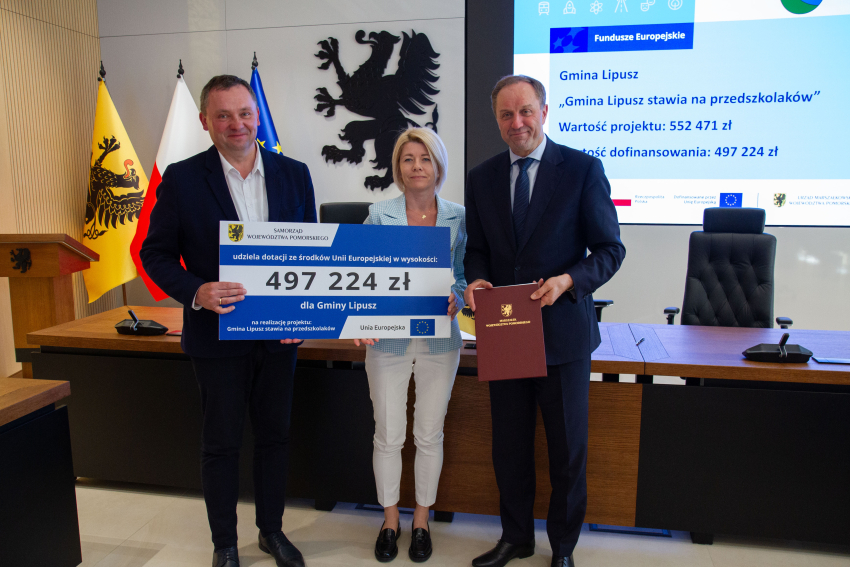 Marszałek Mieczysław Struk i przedstawiciele gminy trzymają czek informujący o dofinansowaniu