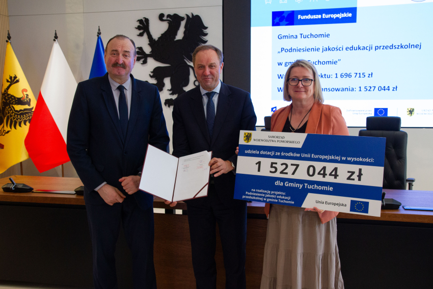 Marszałek i przedstawiciele gminy trzymają czek informujący o dofinansowaniu