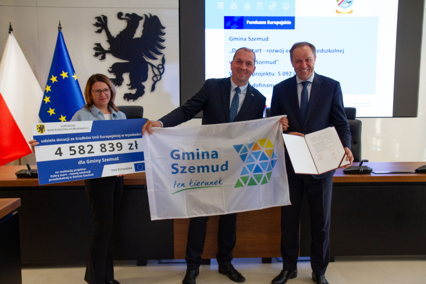 Marszałek i przedstawiciele gminy trzymają czek informujący o dofinansowaniu