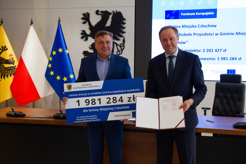 Marszałek Mieczysław Struk i przedstawiciel gminy trzymają czek informujący o dofinansowaniu