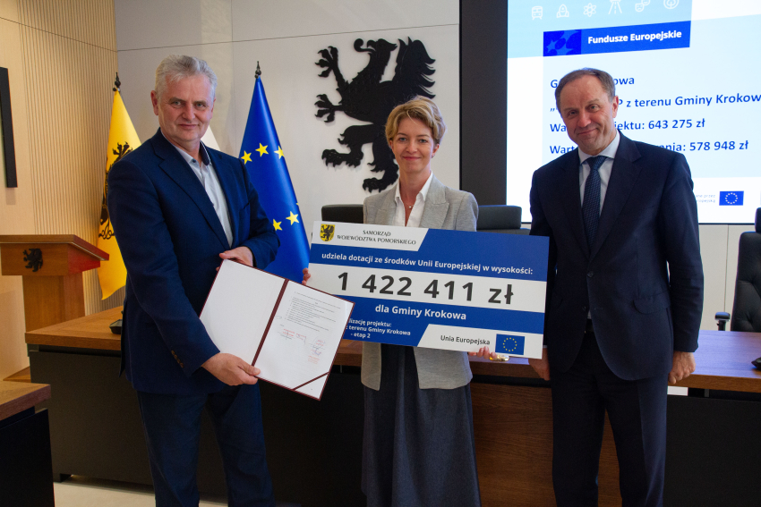 Marszałek Mieczysław Struk i przedstawiciele gminy trzymają czek informujący o dofinansowaniu