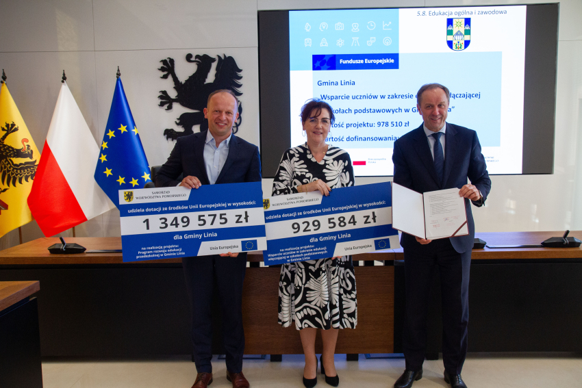 Marszałek Mieczysław Struk i przedstawiciele gminy trzymają czek informujący o dofinansowaniu