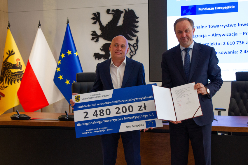 Marszałek Mieczysław Struk i przedstawiciel gminy trzymają czek informujący o dofinansowaniu