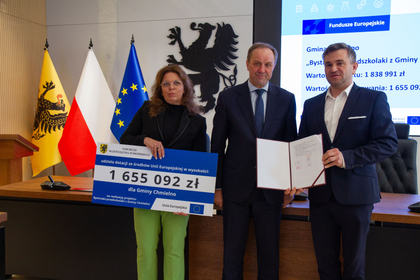 Marszałek Mieczysław Struk i przedstawiciele gminy trzymają czek informujący o dofinansowaniu