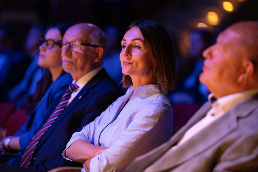 trzy osoby uczestniczące w konferencji, w tle inni