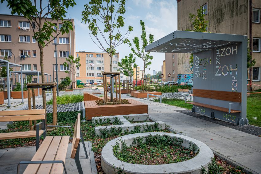 Nowoczesna ławka i architektura w towarzystwie zieleni na tle budynków mieszkalnych