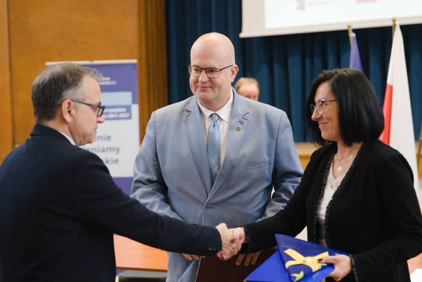 Dyrektor Departamentu Programów Regionalnych Jan Szymański ściska dłoń jakiejś kobiecie, obok stoi inny mężczyzna