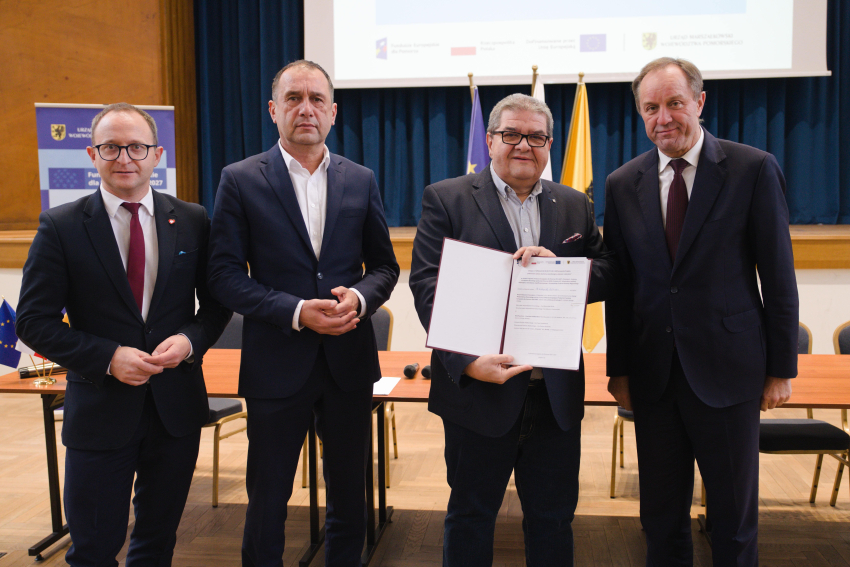 Marszałek Mieczysław Struk, wicemarszałek Marcin Skwierawski i dwie inne osoby prezentują podpisaną umowę