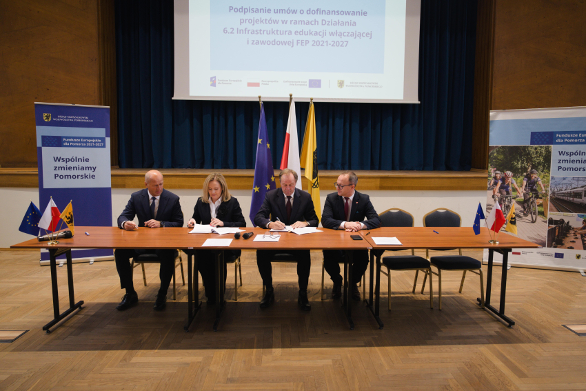 Marszałek Mieczysław Struk, wicemarszałek Marcin Skwierawski i dwie inne osoby podpisują umowę przy stole prezydialnym