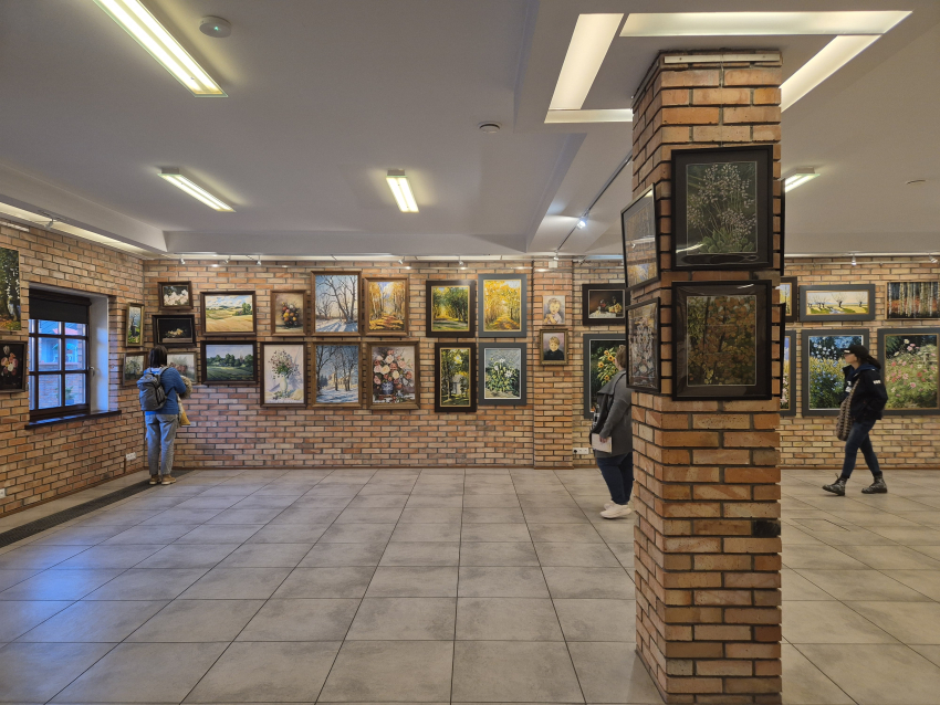 Duża sala z filarem na środku, ścianami z cegły i obrazami na ścianach