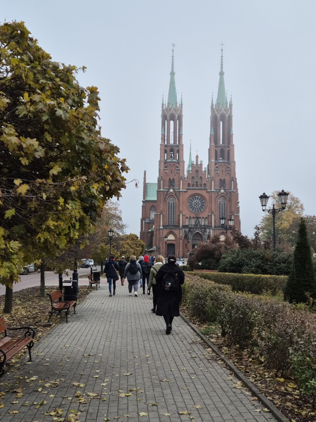 Ludzie idący chodnikiem prowadzącym do kościoła z czerwonej cegły