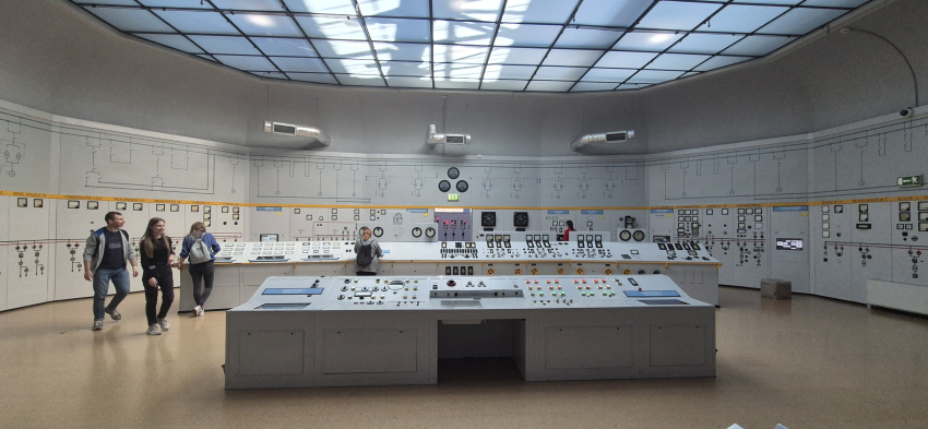 Sala wypełniona urządzeniami sterującymi maszynami, na ścianach różne przyciski i reduktory