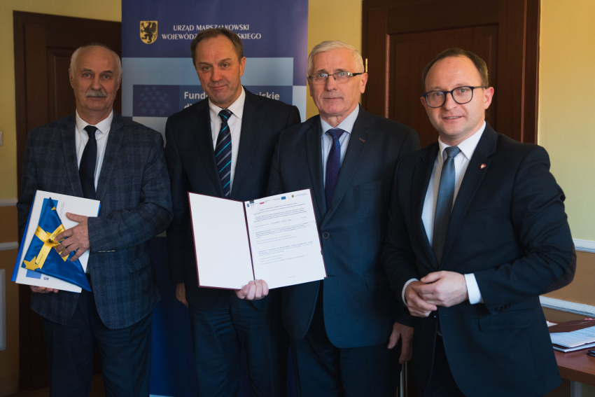 Cztery osoby prezentują podpisaną umowę, w tym marszałek Mieczysław Struk oraz wicemarszałek Marcin Skwierawski