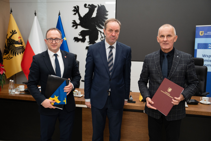 Marszałek Mieczysław Struk, wicemarszałek Marcin Skwierawski i jeden z przedstawicieli władz lokalnych prezentują podpisaną umowę i flagę Unii Europejskiej.