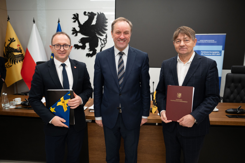 Marszałek Mieczysław Struk, wicemarszałek Marcin Skwierawski i jeden z przedstawicieli władz lokalnych prezentują podpisaną umowę i flagę Unii Europejskiej.