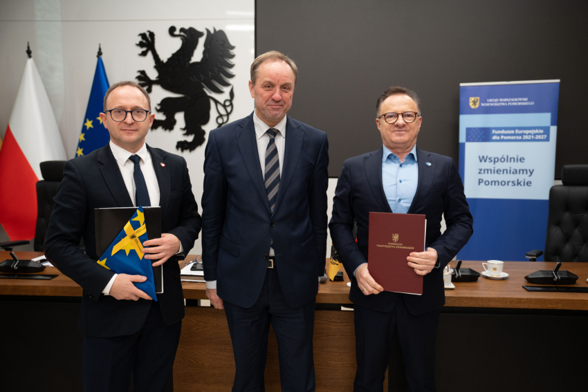 Marszałek Mieczysław Struk, wicemarszałek Marcin Skwierawski i jeden z przedstawicieli władz lokalnych prezentują podpisaną umowę i flagę Unii Europejskiej.