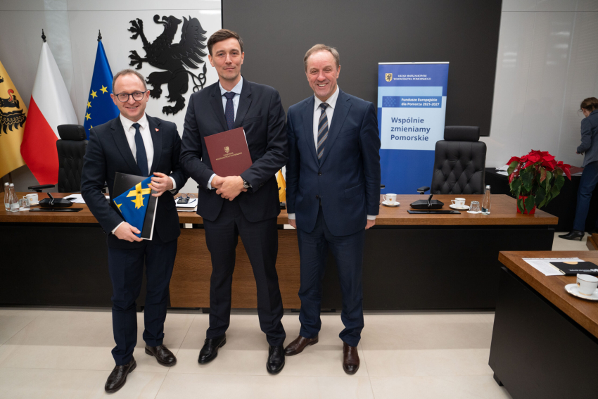Marszałek Mieczysław Struk, wicemarszałek Marcin Skwierawski i jeden z przedstawicieli władz lokalnych prezentują podpisaną umowę i flagę Unii Europejskiej.
