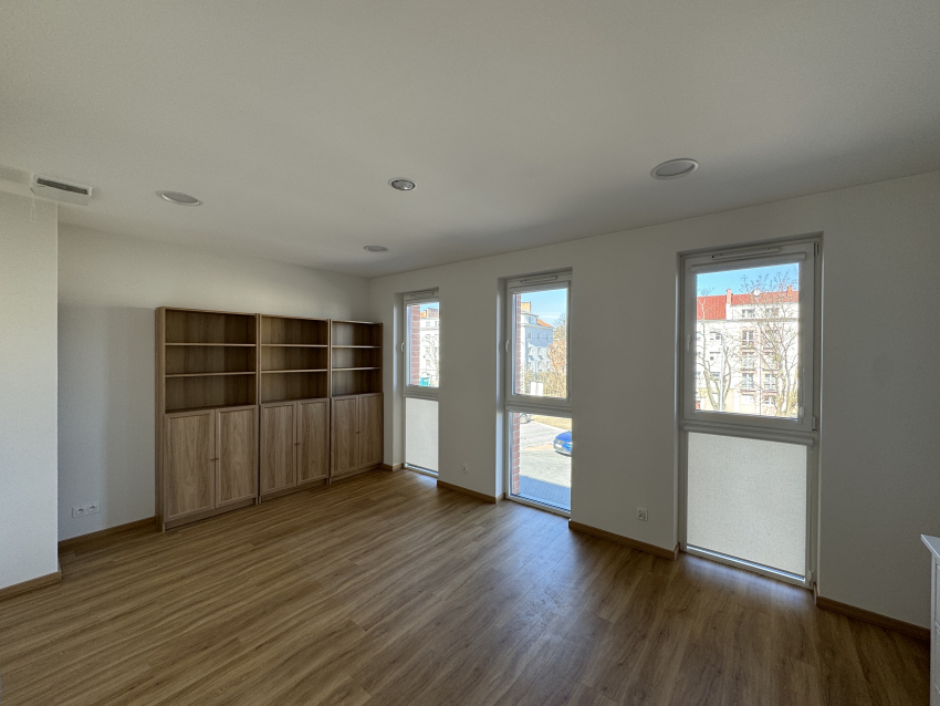 Pokój dla osoby z autyzmem w budynku. W ujęciu trzy półki na książki oraz trzy duże okna