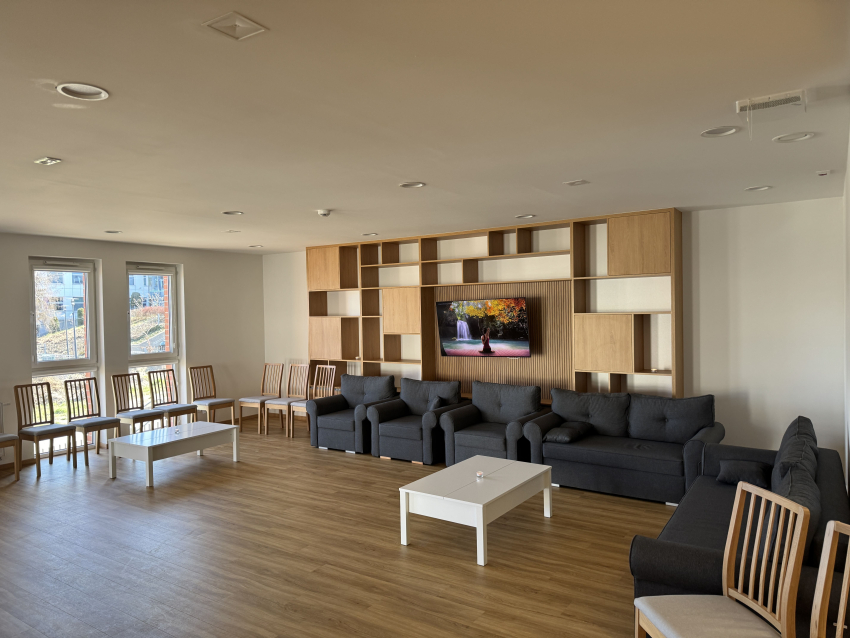 Przestrzeń wspólna budynku. Krzesła, sofy, telewizor, regały na książki