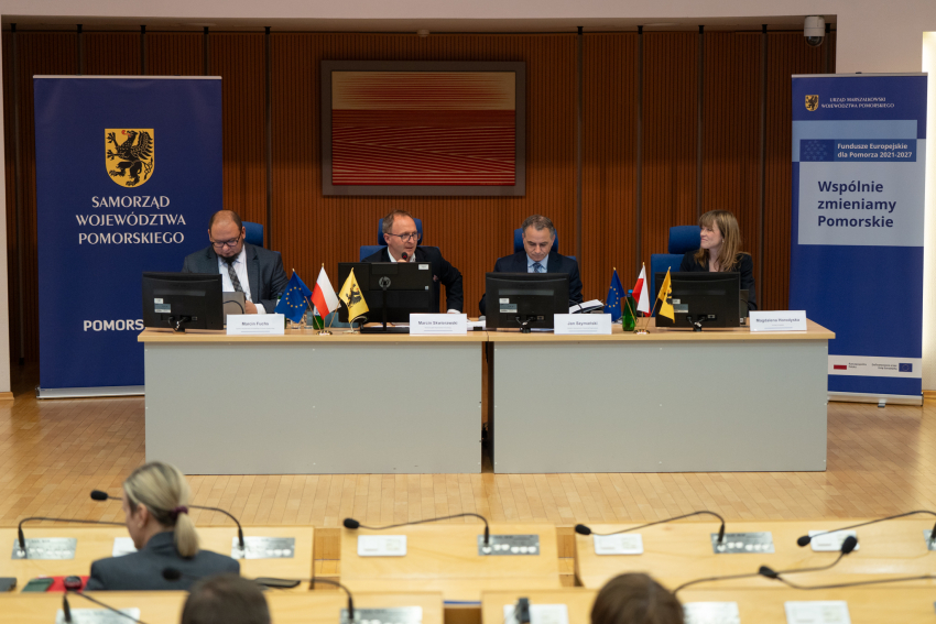 Na zdjęciu widać cztery osoby siedzące przy stole prezydialnym.