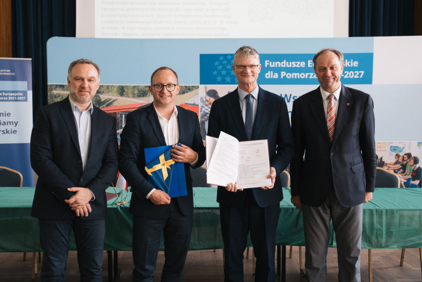 Marszałek Mieczysław Struk, wicemarszałek Marcin Skwierawski oraz dwóch przedstawicieli jednej z gmin prezentują podpisaną umowę oraz flagę Unii Europejskiej.