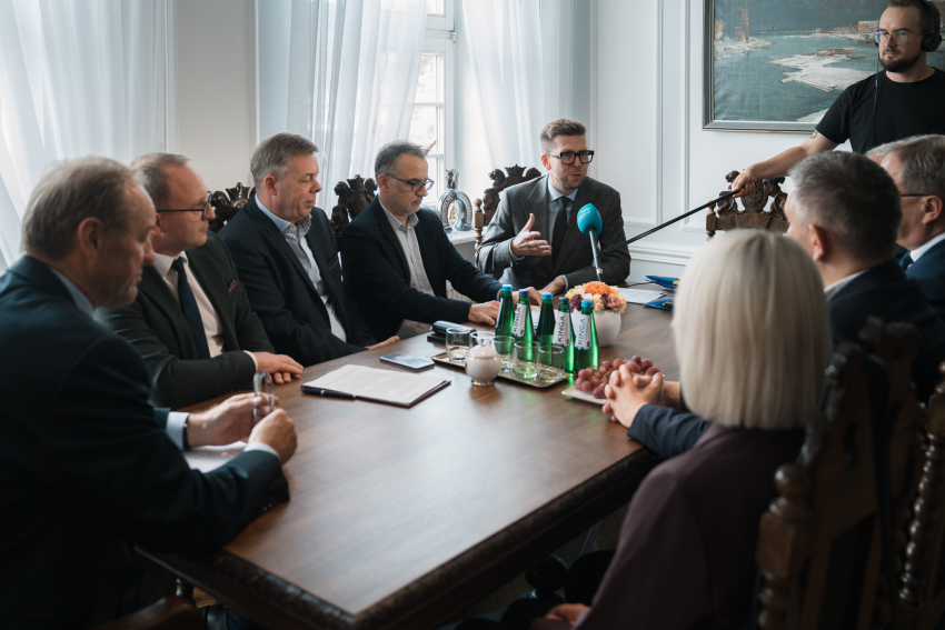 Przy stole siedzi dziewięciu uczestników wydarzenia, wśród nich marszałek Mieczysław Struk, wicemarszałek Marcin Skwierawski, dyrektor Departamentu Programów Regionalnych Jan Szymański, prezydent Starogardu Gdańskiego Janusz Stankowiak oraz wójt gminy Chmielno Michał Melibruda. Stoi również mężczyzna z mikrofonem z Radia Gdańsk