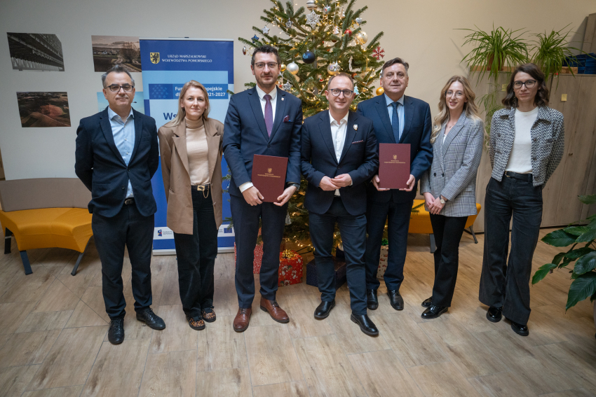 Elegancko ubrani ludzie z dokumentami, w tle choinka