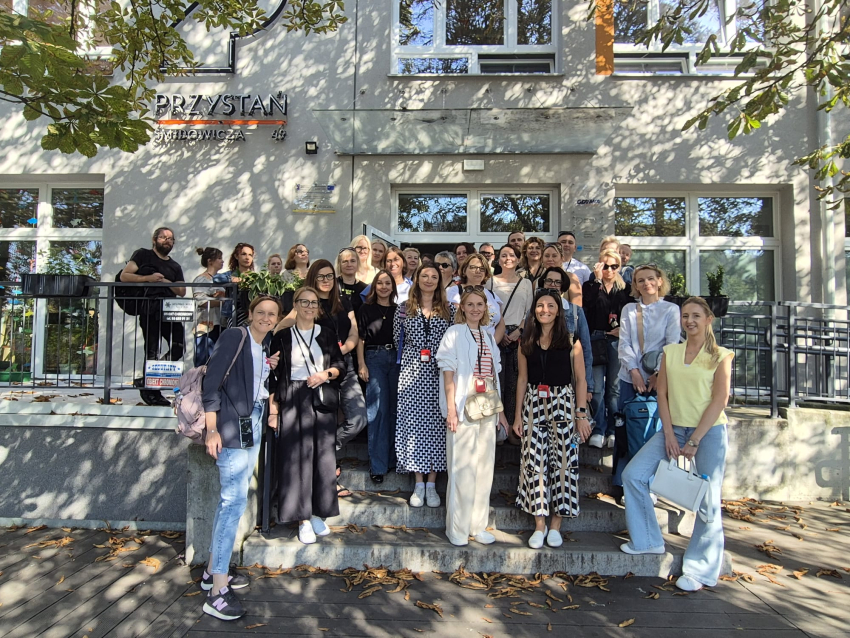 Grupa ludzi stojąca na schodach przy wejściu do budynku