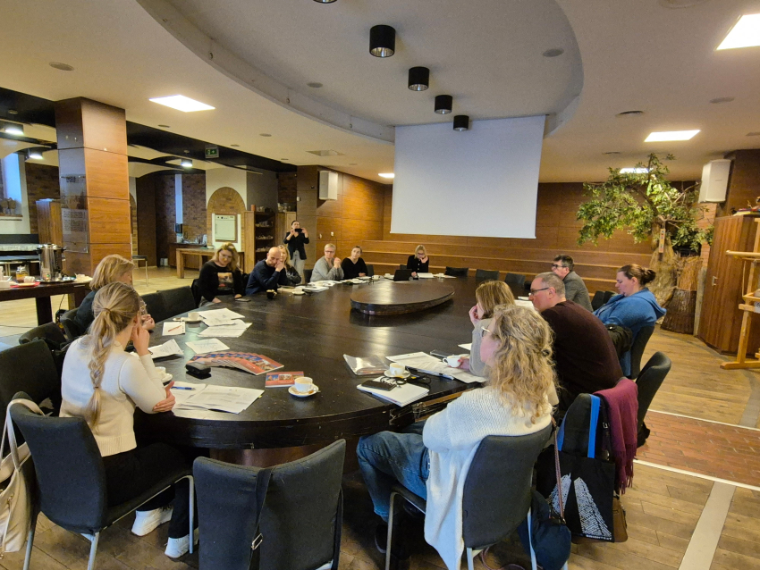 Grupa ludzi siedząca przy okrągłym stole