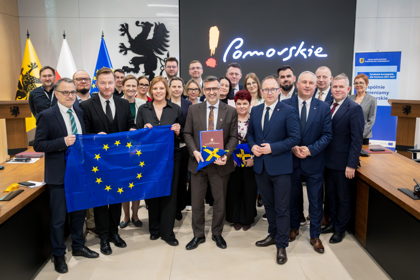 Grupa osób prezentuje podpisane umowy