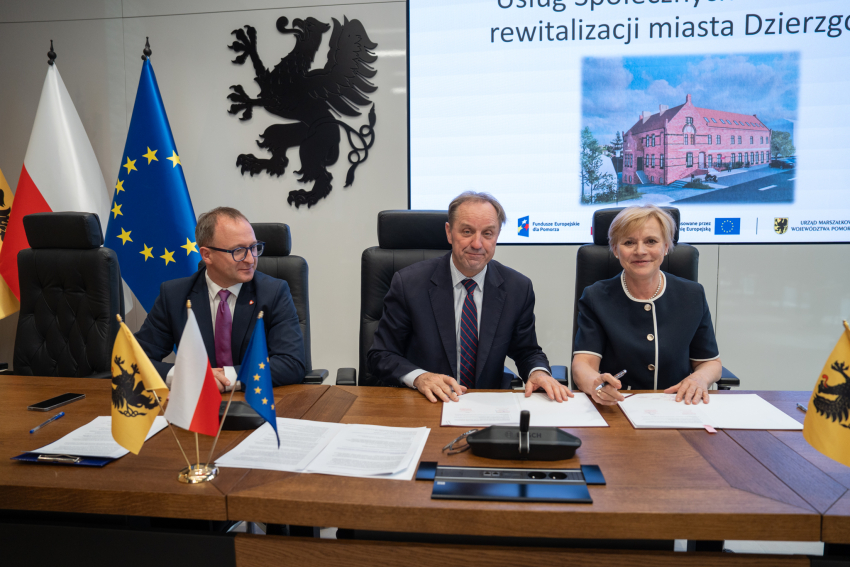 Marszałek Mieczysław Struk, wicemarszałek Marcin Skwierawski oraz przedstawicielka władz regionu siedzą przy stole prezydialnym i podpisują umowę