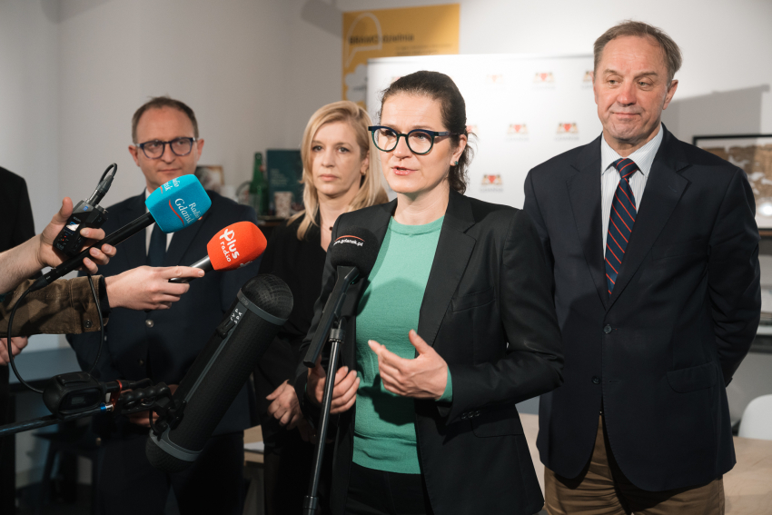 prezydent Gdańska Aleksandra Dulkiewicz udziela wywiadu do mikrofonu. Obok stoją wicemarszałek Marcin Skwierawski oraz marszałek Mieczysław Struk