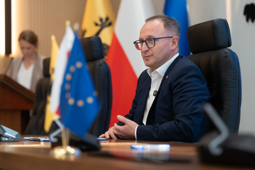 Wicemarszałek Marcin Skwierawski podpisuje siedzi przy stole prezydialnym i przemawia do zebranych