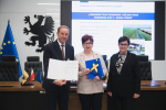 Marszałek Województwa Pomorskiego - Mieczysław Struk, wójt gminy Stegna oraz skarbnik gminy Stegna - Dorota Witkowska, pozują do uroczystego zdjęcia prezentując podpisaną umową o dofinansowanie i flagę Unii Europejskiej