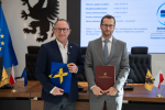 Wicemarszałek Marcin Skwierawski oraz przedstawiciel Powiatowego Centrum Zdrowia Sp. z o.o. pozują do uroczystego zdjęcia prezentując podpisaną umowę o dofinansowanie oraz flagę UE