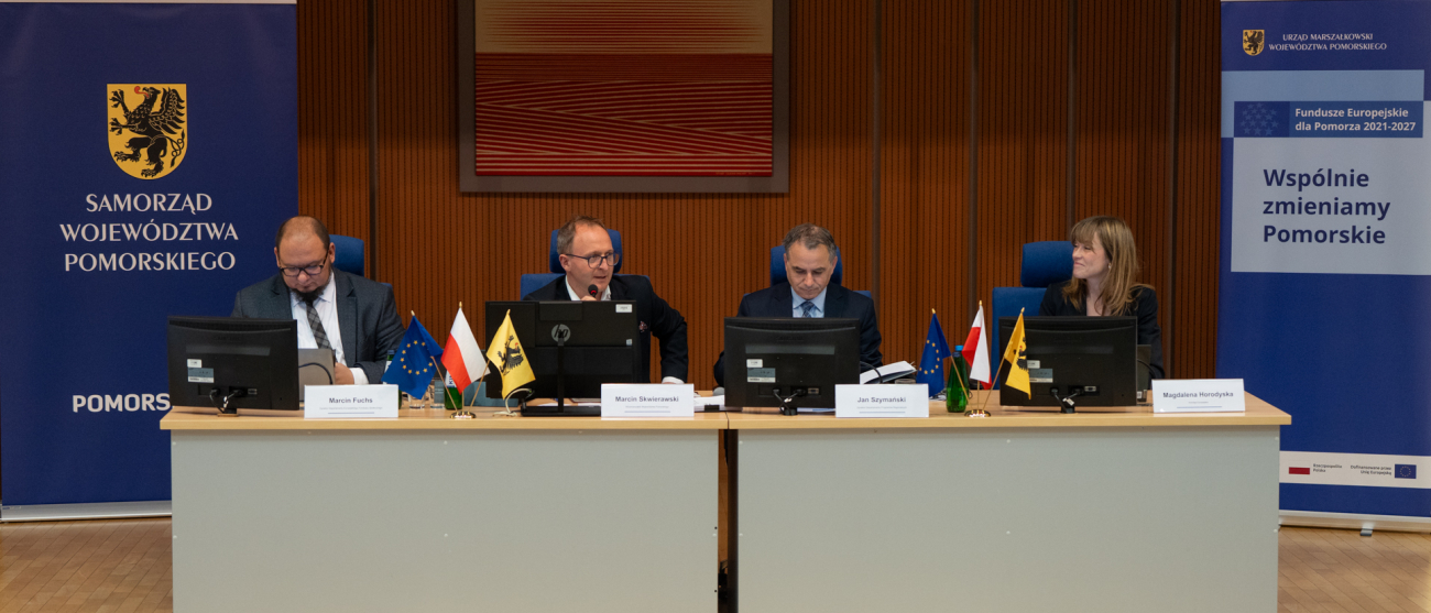 Na zdjęciu widać cztery osoby siedzące przy stole prezydialnym.