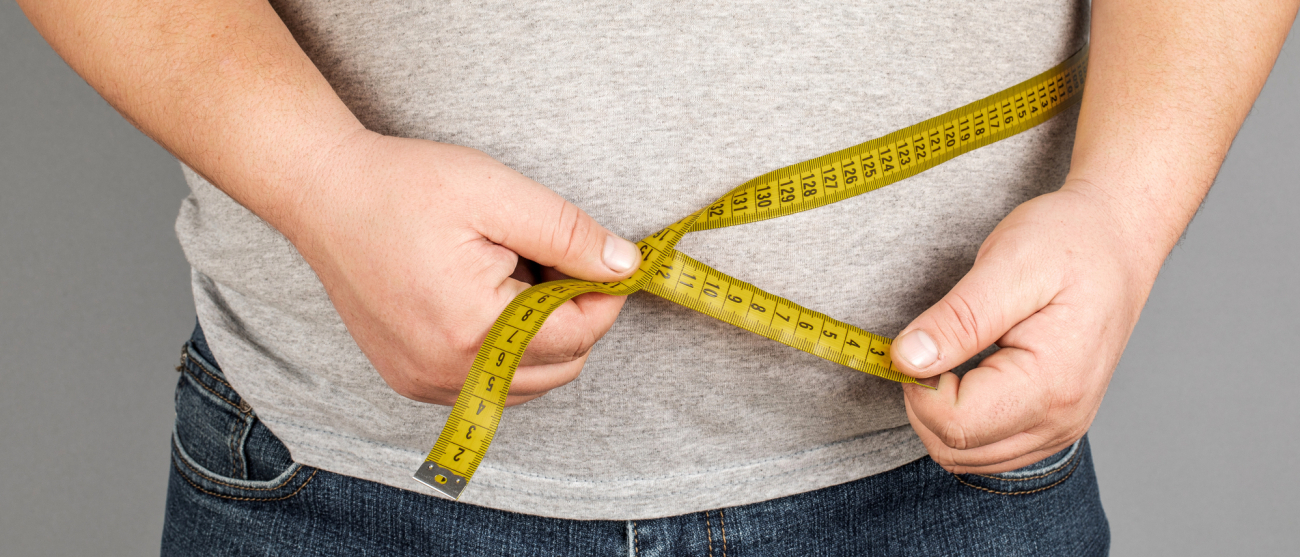 Mężczyzna w szarym t-shircie. Ma miarę krawiecką na brzuchu