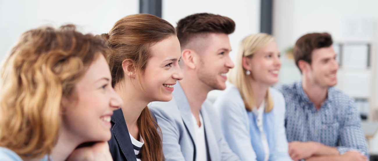 pięciu uśmiechniętych pracowników biurowych słucha kogoś