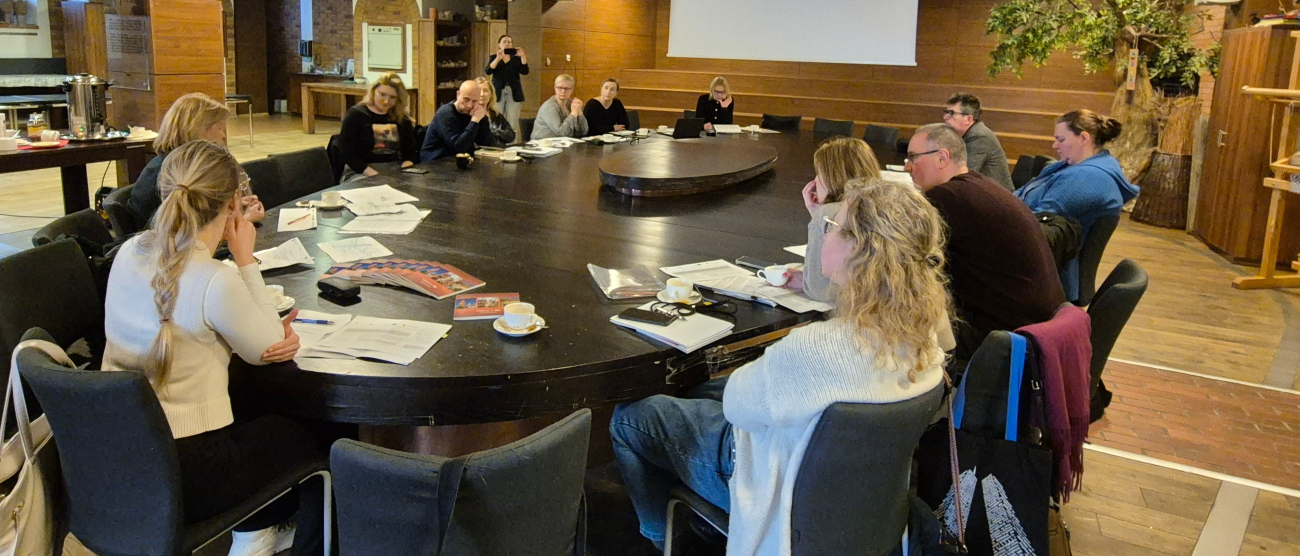 Grupa ludzi siedząca przy okrągłym stole