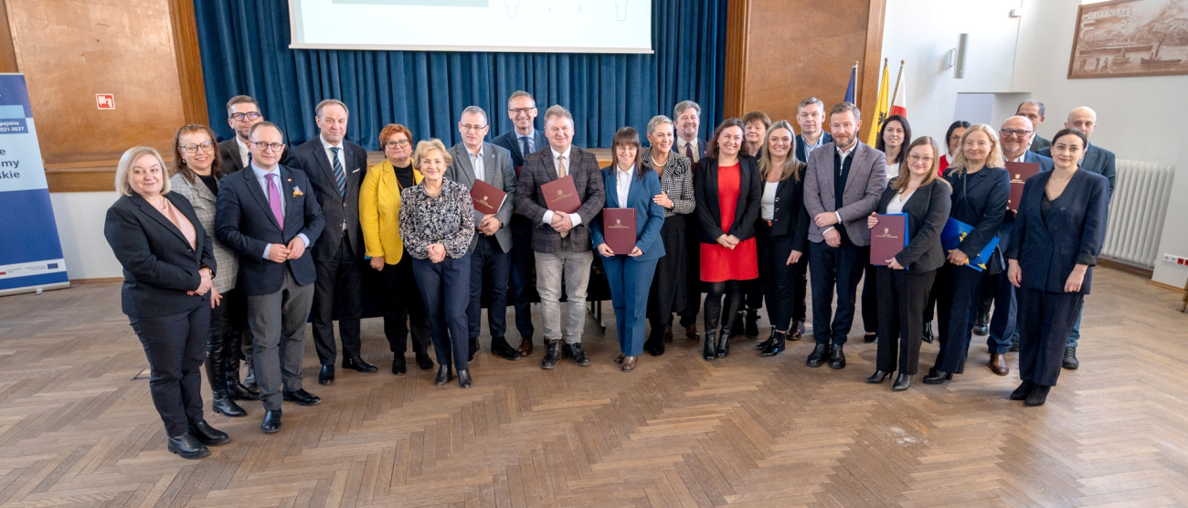 grupa osób przedstawia podpisaną Umowę