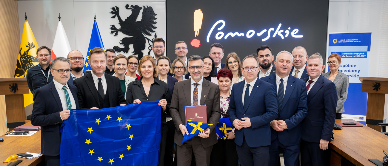 Grupa osób prezentuje podpisane umowy