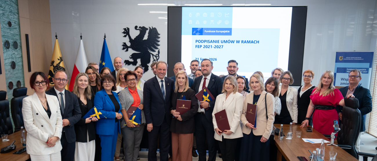 Grupa ludzi podczas uroczystego podpisania umów. 